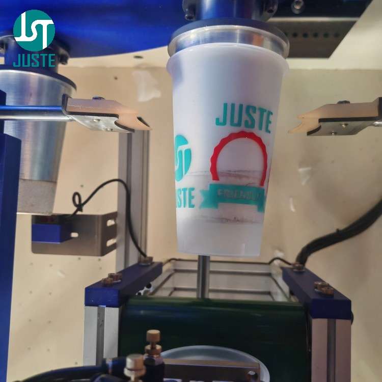 Robotic arm loading cup into 8-station turntable on automatic screen printer